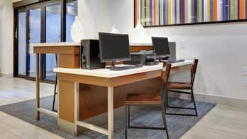 A reception desk with two computer stations, a chair, and a modern art piece on the wall.