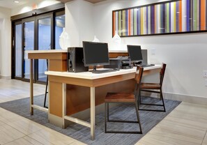 A reception desk with two computer stations, a chair, and a modern art piece on the wall. - Holiday Inn Express & Suites Denton North by IHG (Denton)
