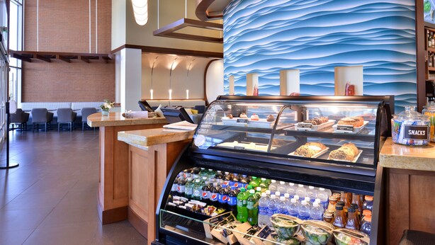 A bakery counter with pastries and a beverage display. - Hyatt Place Garden City (Garden City)