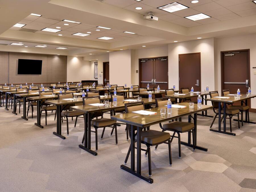 A conference room with multiple tables, chairs, and water bottles.