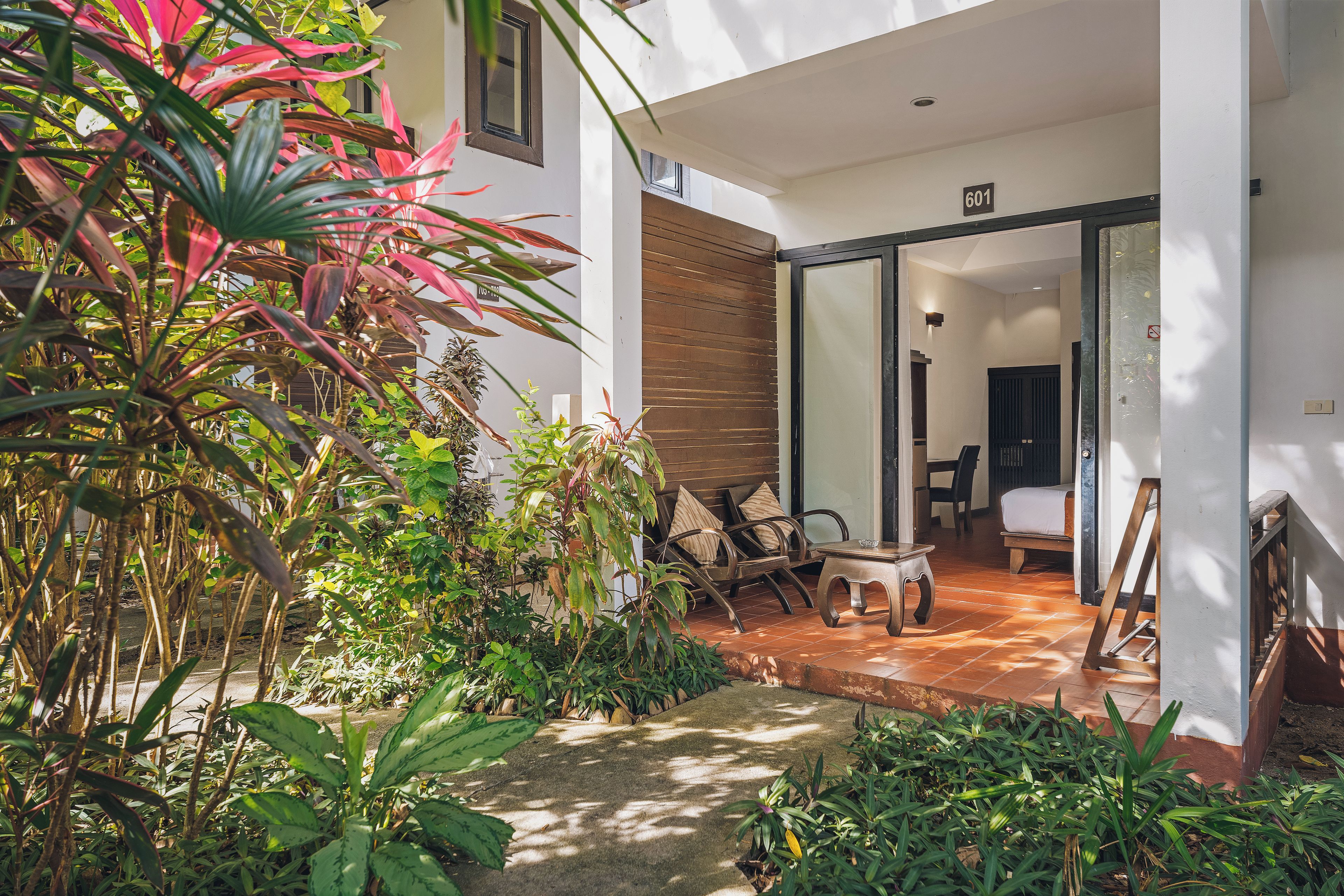 A hotel room with a view of the garden, a dining area with chairs and a table, and a bed with a view of the garden.