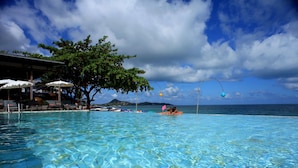 A clear pool with a view of the ocean and a tree. - The Hive Hotel Samui (Koh Samui)