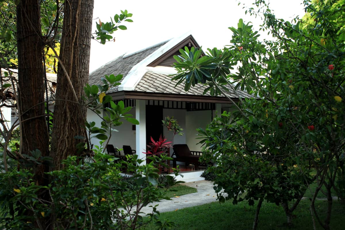 A house with a sloped roof, surrounded by lush greenery and trees.
