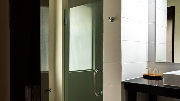 A bathroom with a glass door, a sink, and a mirror. - The Hive Hotel Samui (Koh Samui)