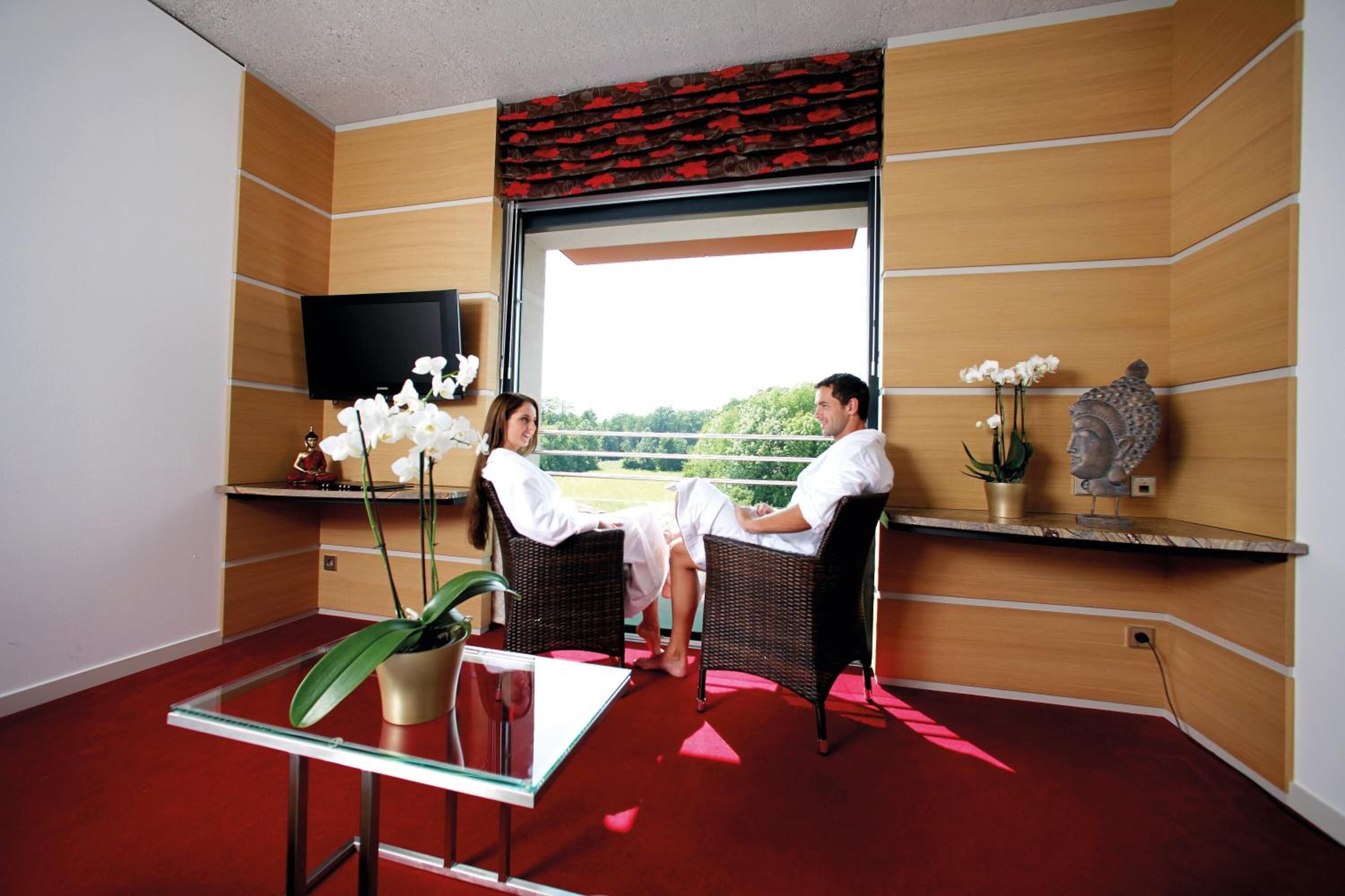 Ein modernes Zimmer mit Korbmöbeln, einem Glastisch und einem Fernseher an der Wand.