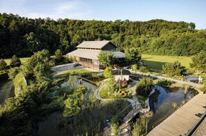 A lodge with a large building, a pond, and a forested area. - Asia Resort Linsberg - Adults Only (Bad Erlach)