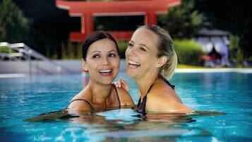 Two people in a swimming pool with a red structure in the background.