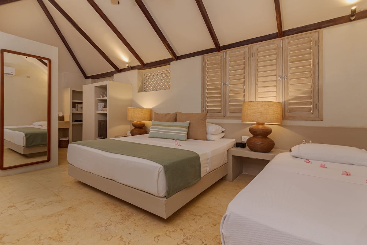 Una camera d'albergo con un letto grande, comodini, uno specchio e un armadio.