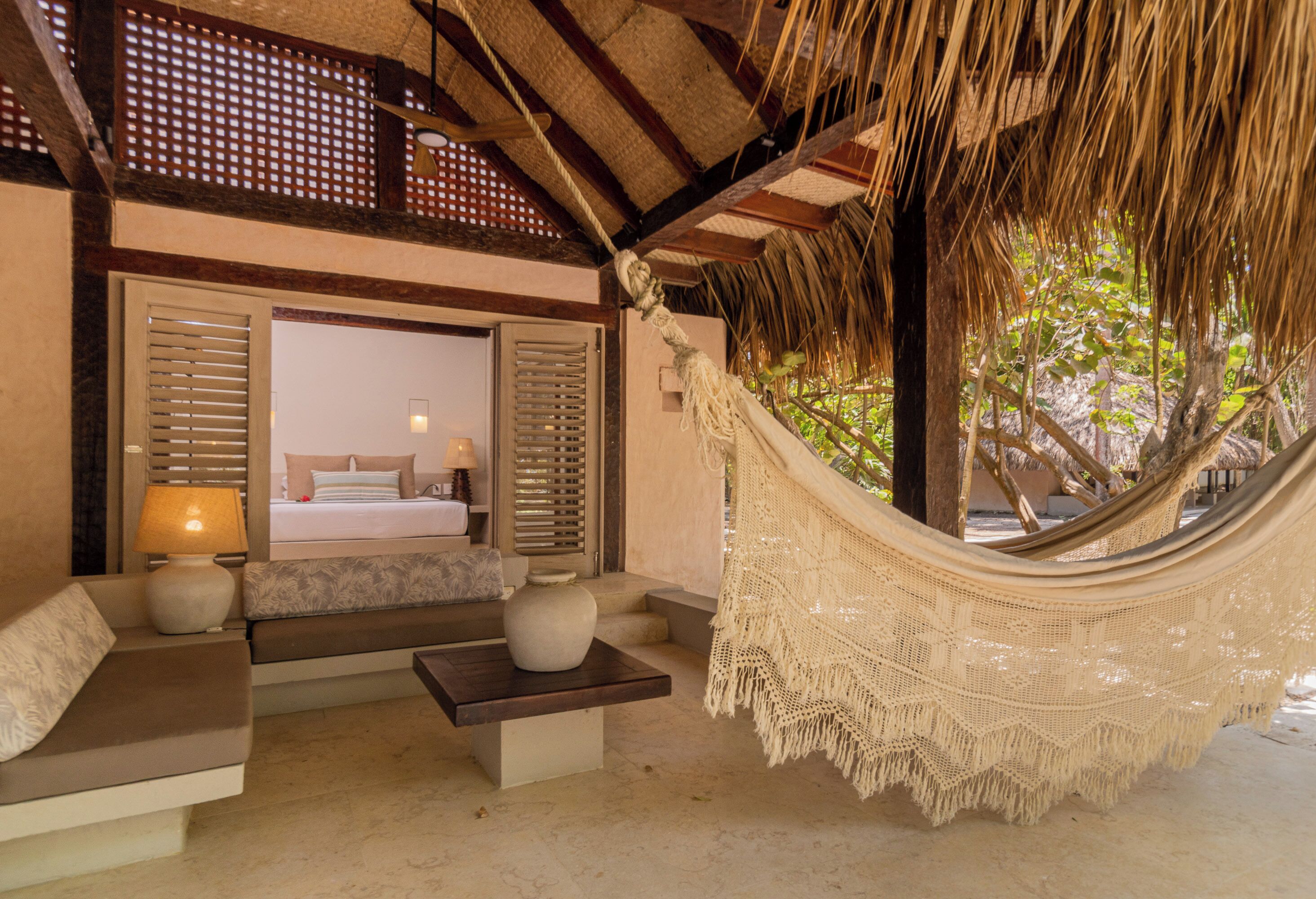 A hammock in a room with a bed, a sofa, and a table.