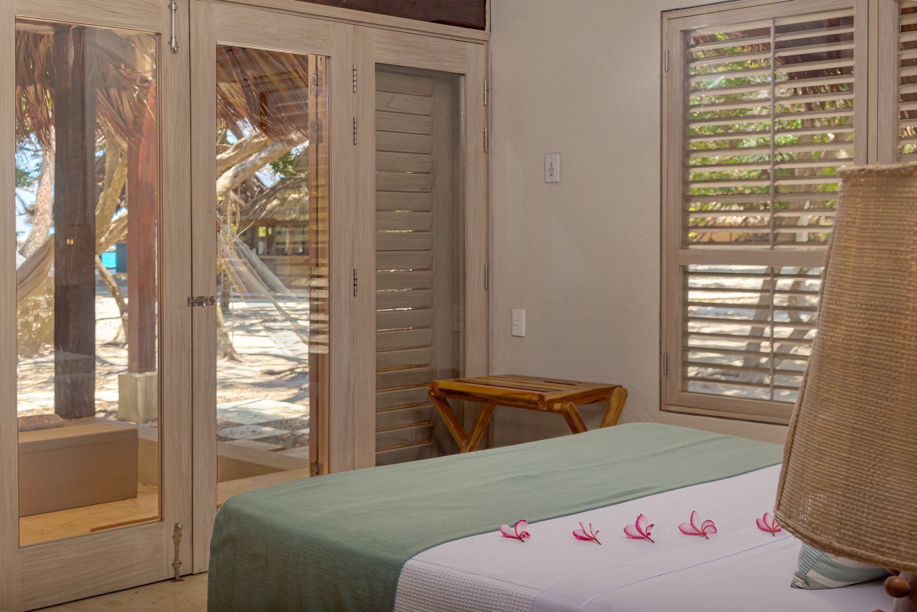 A room with a bed, a small wooden table, and a window with blinds.