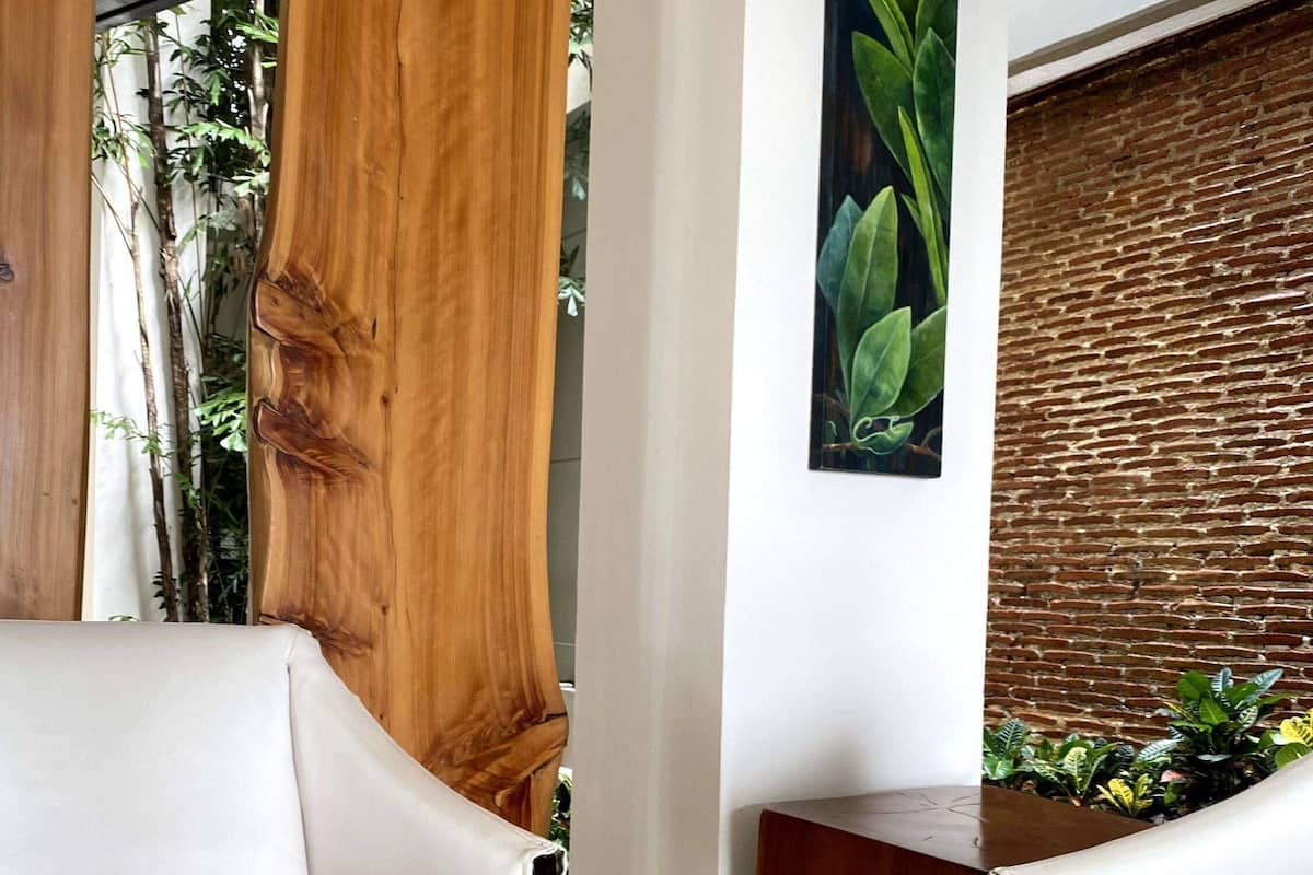 Un salon moderne avec une table basse en verre, des canapés en cuir blanc, un mur d’accent en bois et une plante posée sur la table.