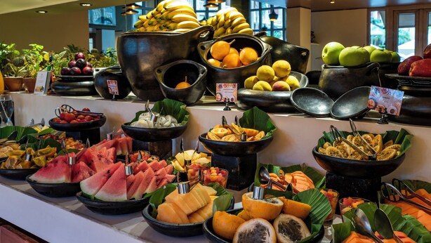 A buffet with various fruits and vegetables displayed in large bowls and pots.
