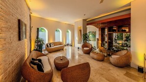 A spacious living area with wicker furniture, a brick wall, and a view of the outdoors. - Hotel Boutique Bovedas de Santa Clara By Accor (Cartagena)