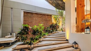 A modern outdoor staircase with wooden steps and black lanterns, leading to a brick wall with greenery. - Hotel Boutique Bovedas de Santa Clara By Accor (Cartagena)
