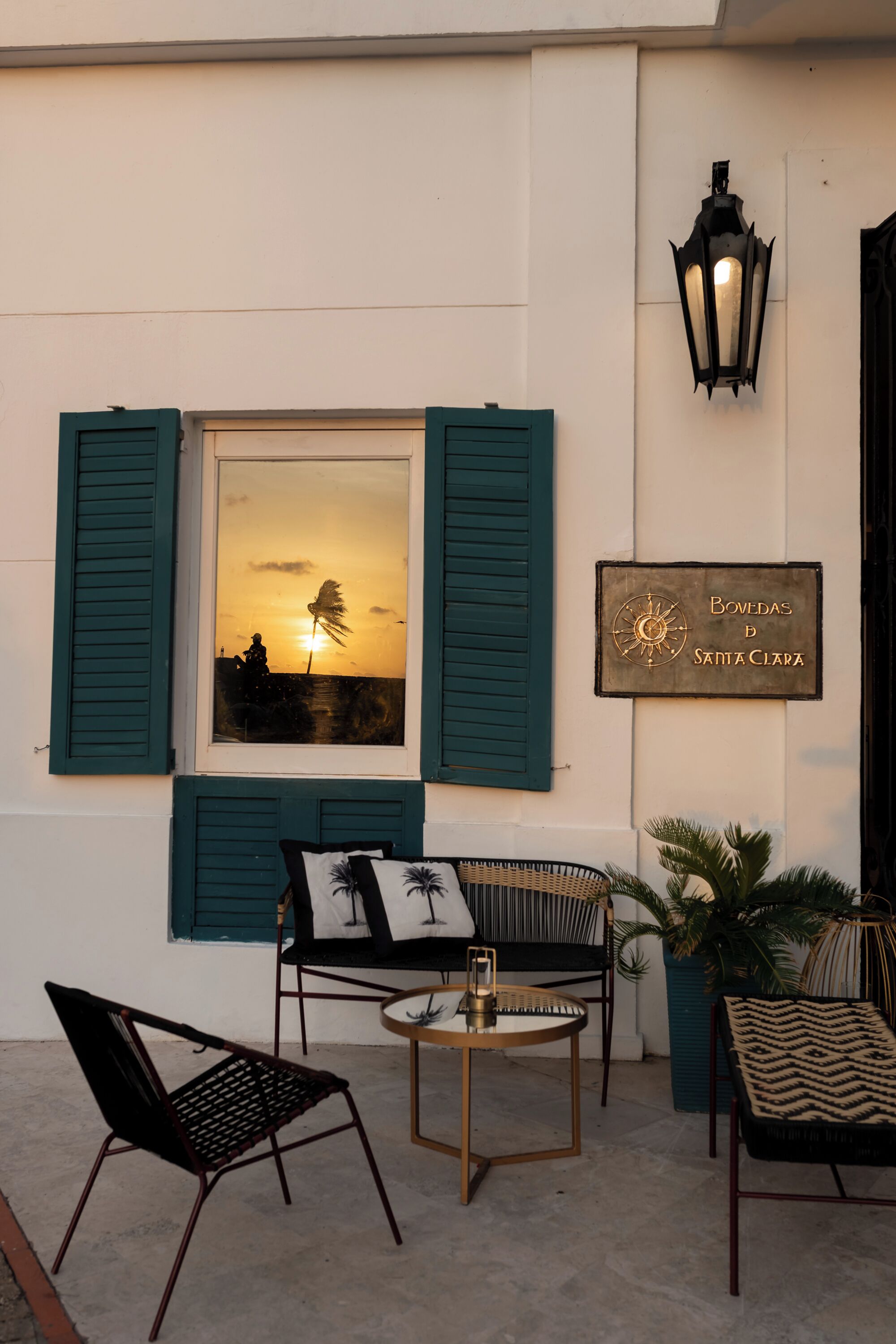 A terrace with a view of the sunset, a sign reading "Bovedas de Santa Clara", and outdoor furniture.