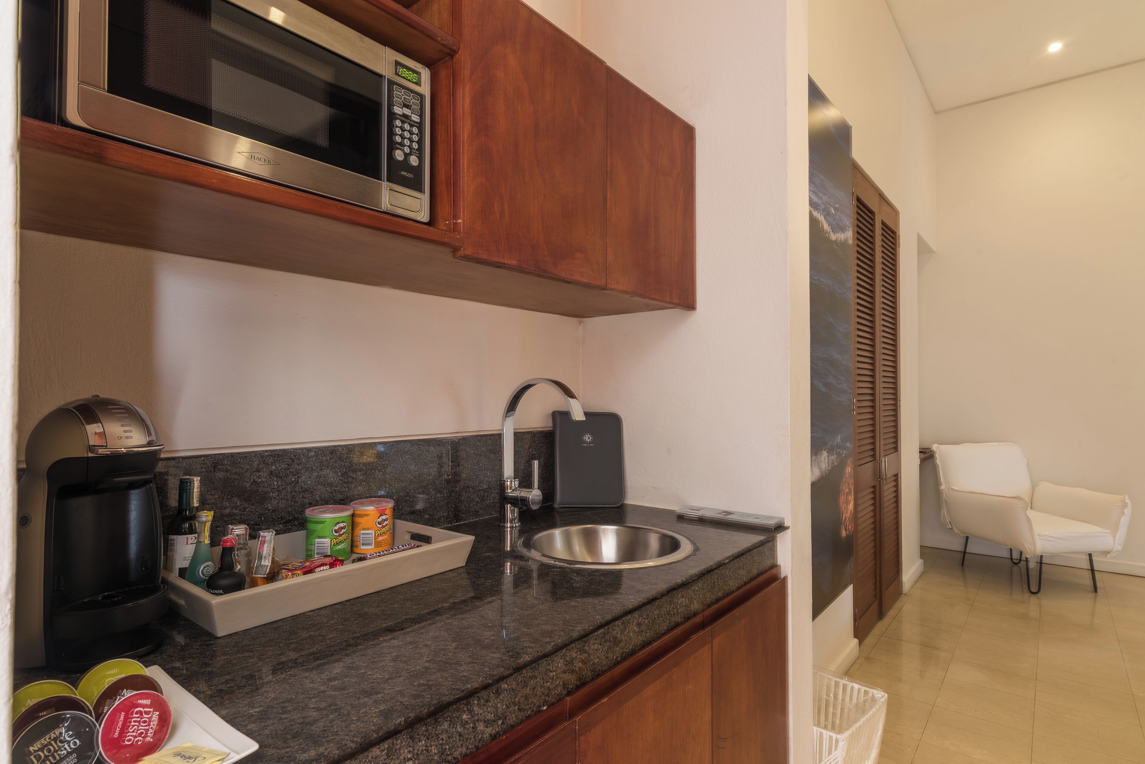 Una cocina compacta con microondas, cafetera y lavabo.