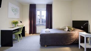 A bedroom with a bed, a desk, a chair, a window with curtains, and a wall-mounted artwork. - Hotel Bakfickan (Stockholm)