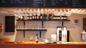 A bar area with a variety of bottles and glasses on shelves, a coffee machine, and a menu on the wall. - Hotel Bakfickan (Stockholm)