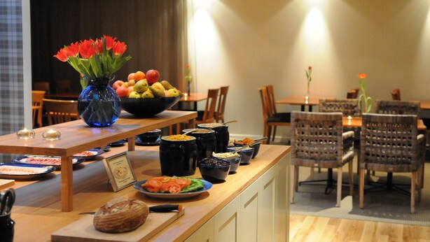 A buffet setup with various food items and a vase of red flowers. - Hotel Bakfickan (Stockholm)