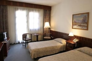 A hotel room with two beds, a desk, a chair, a television, and a painting on the wall. - Hortobagy Club Hotel (Hortobágy)