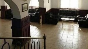 A spacious interior with a high ceiling, a balcony with metal railings, and a seating area with sofas.