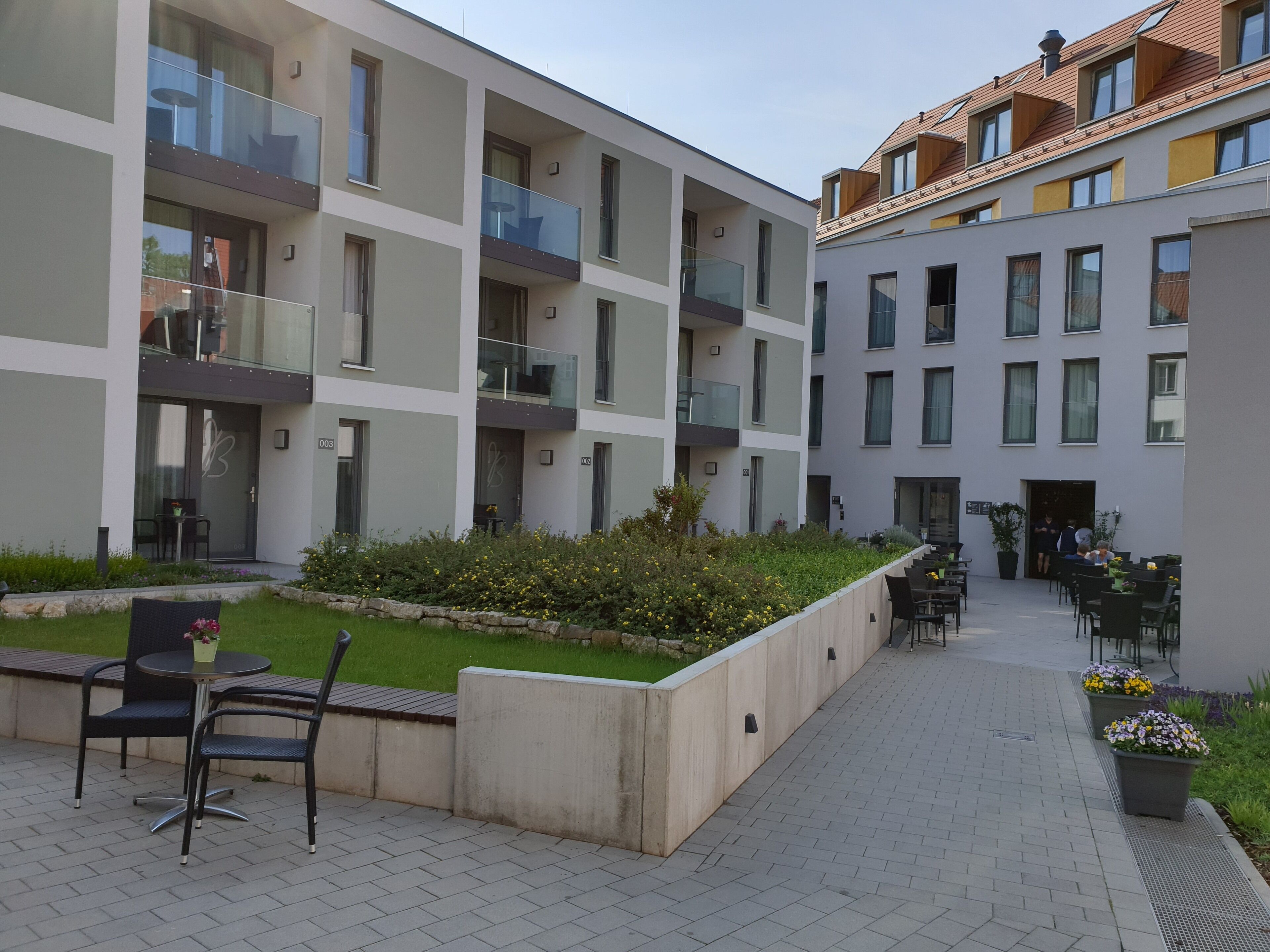 Ein modernes Apartmenthaus mit Balkonen, Sitzgelegenheiten im Freien und einem angelegten Garten.