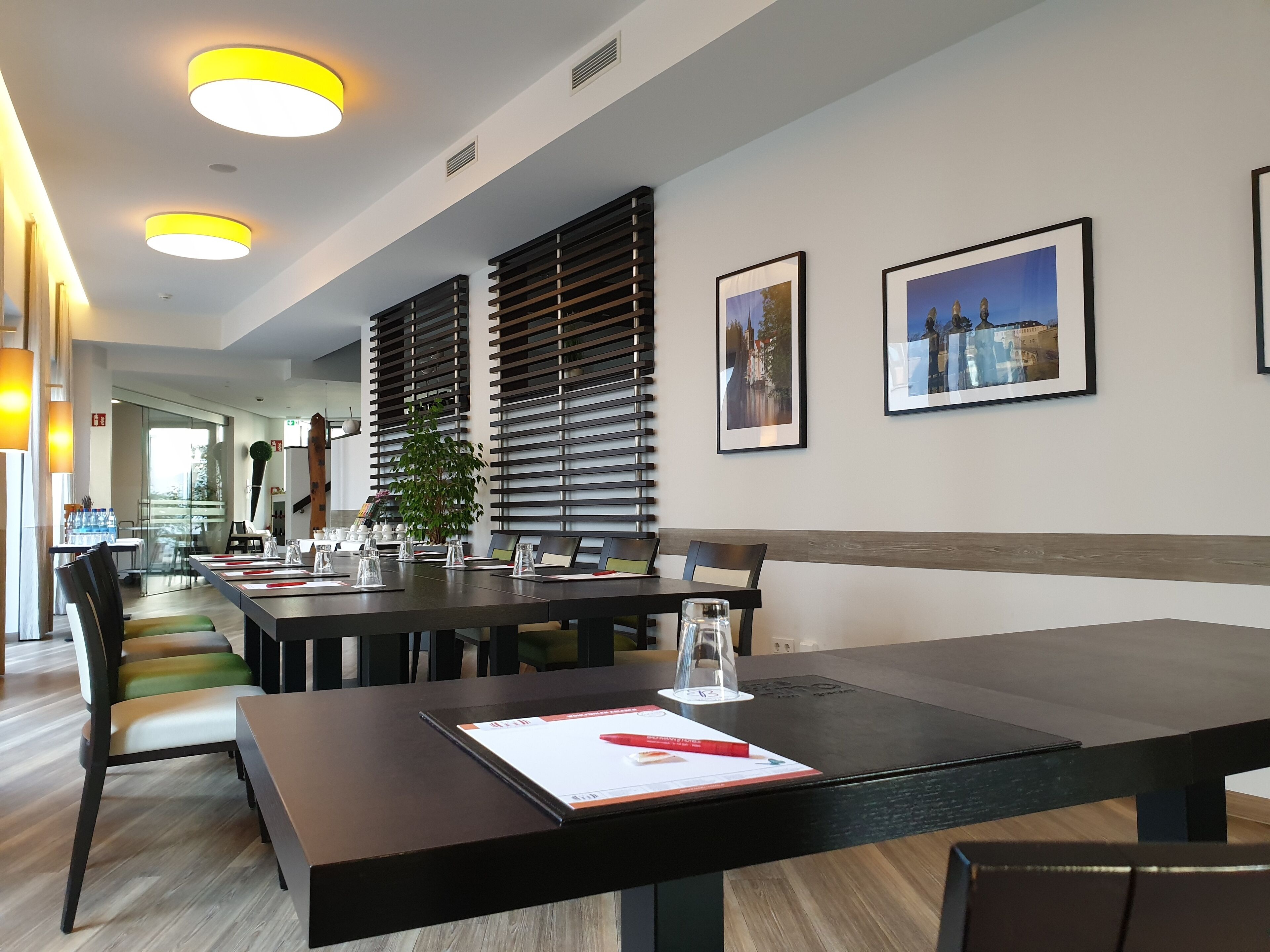 A modern conference room with a long table, chairs, and a potted plant.