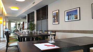 A modern conference room with a long table, chairs, and a potted plant.