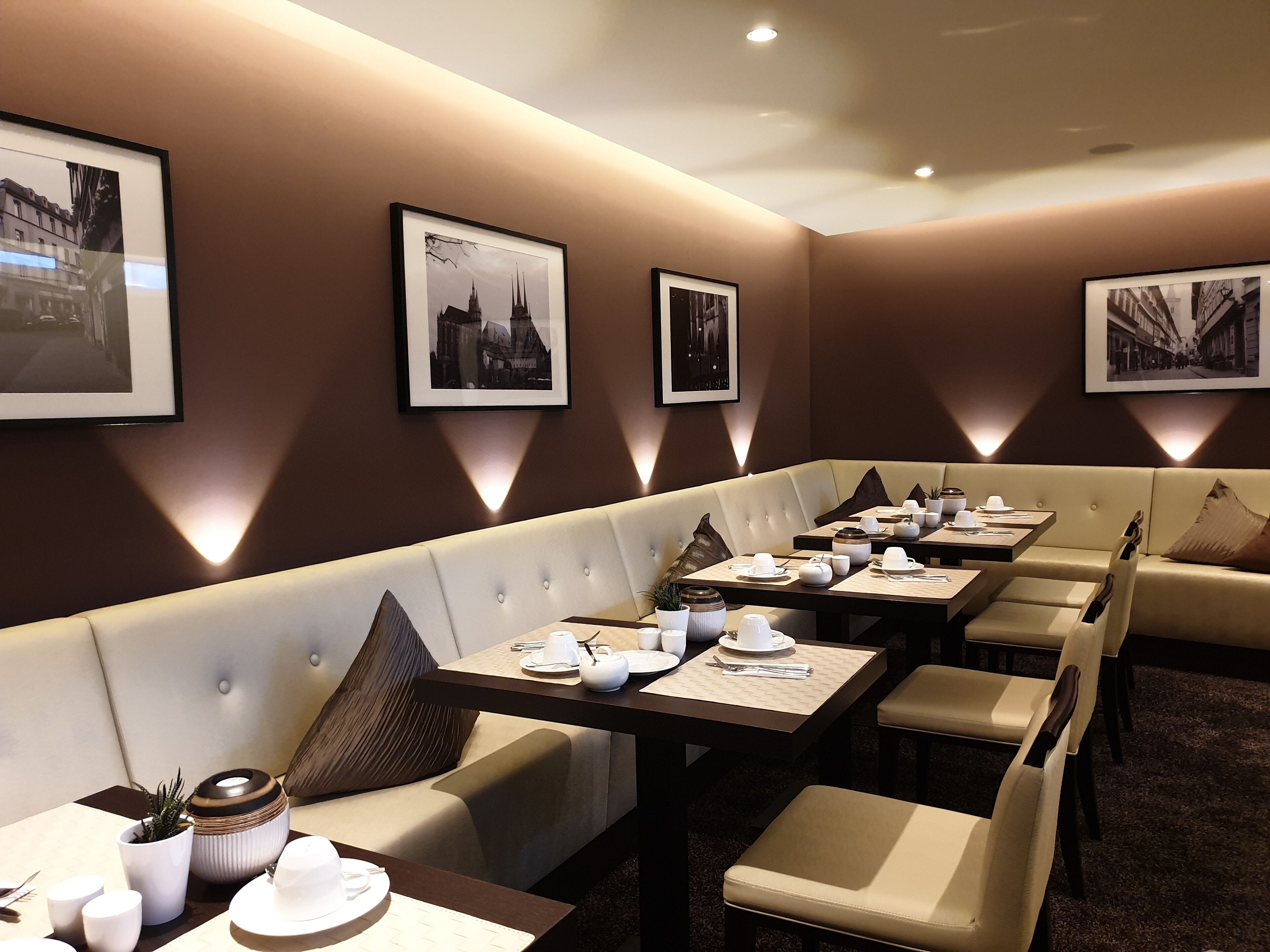 A restaurant with booths and tables, each set with plates, cups, and cutlery.