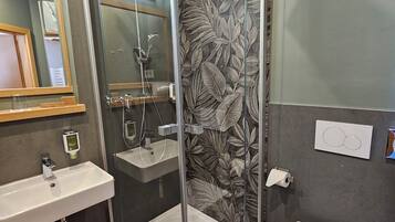 A modern bathroom with a glass-enclosed shower, a sink, and a toilet.