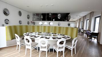 Un comedor moderno con una mesa redonda, sillas blancas y una pared con estampado amarillo.