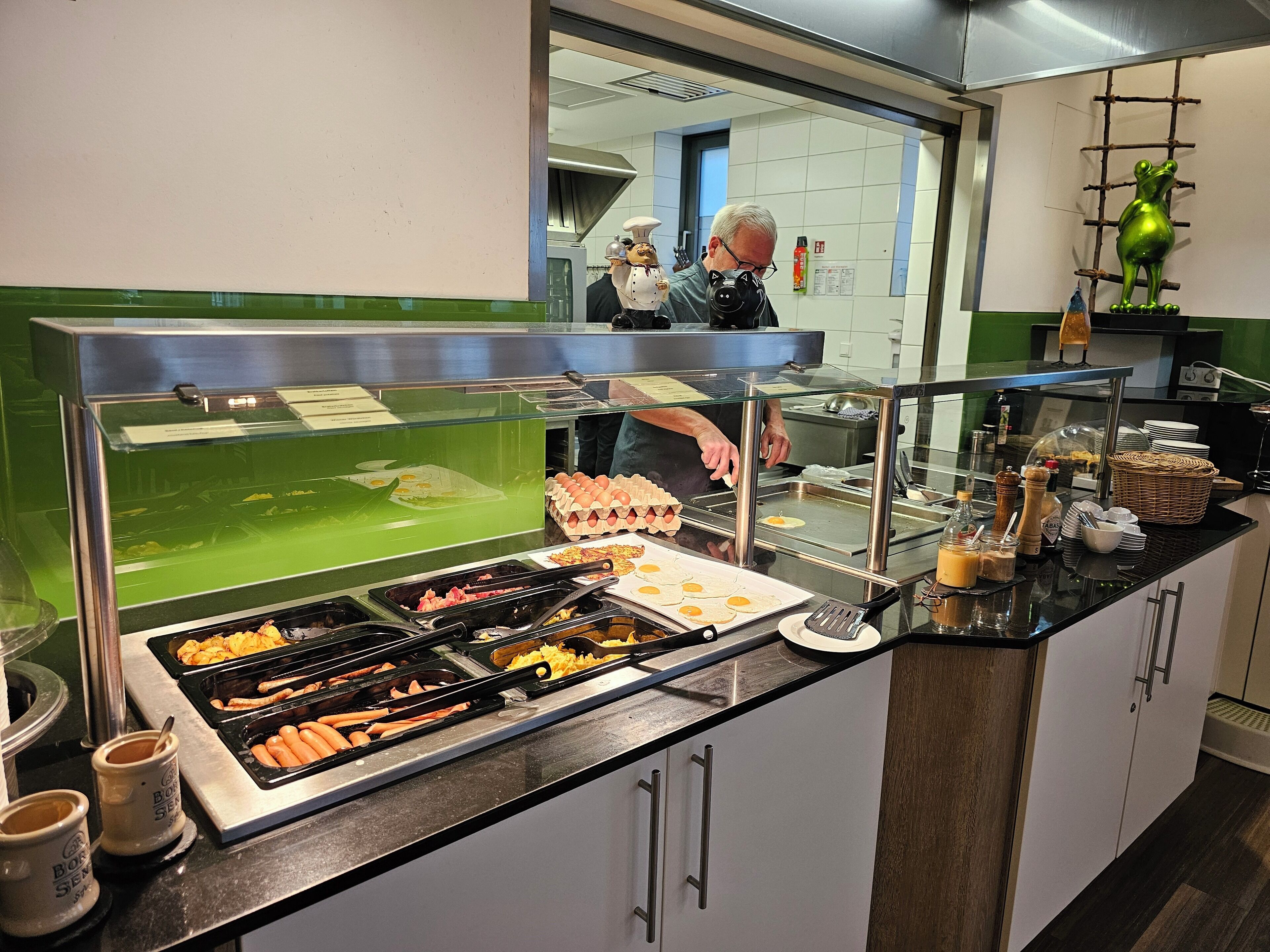 Un'area buffet con diverse opzioni alimentari tra cui uova, salsicce e hot dog.