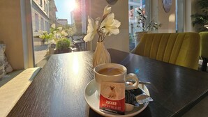 Una mesa con una taza de café, un termo y un plato con una bolsita de té y una caja con la etiqueta "ZUCKER MOPSEIN ERLAUBT".