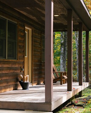 A log cabin with a porch, a door, and a window.