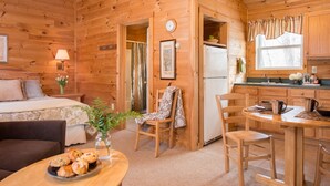 Eine Holzhütte mit einem Bett, einem Essbereich, einer Küche und einem Badezimmer.