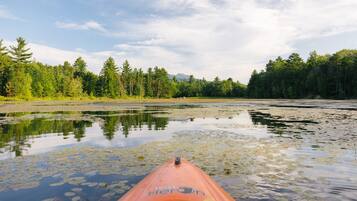 A kayak on a calm river with reflections of trees and a clear sky.