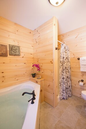 A wooden-paneled bathroom with a bathtub, toilet, and shower curtain.
