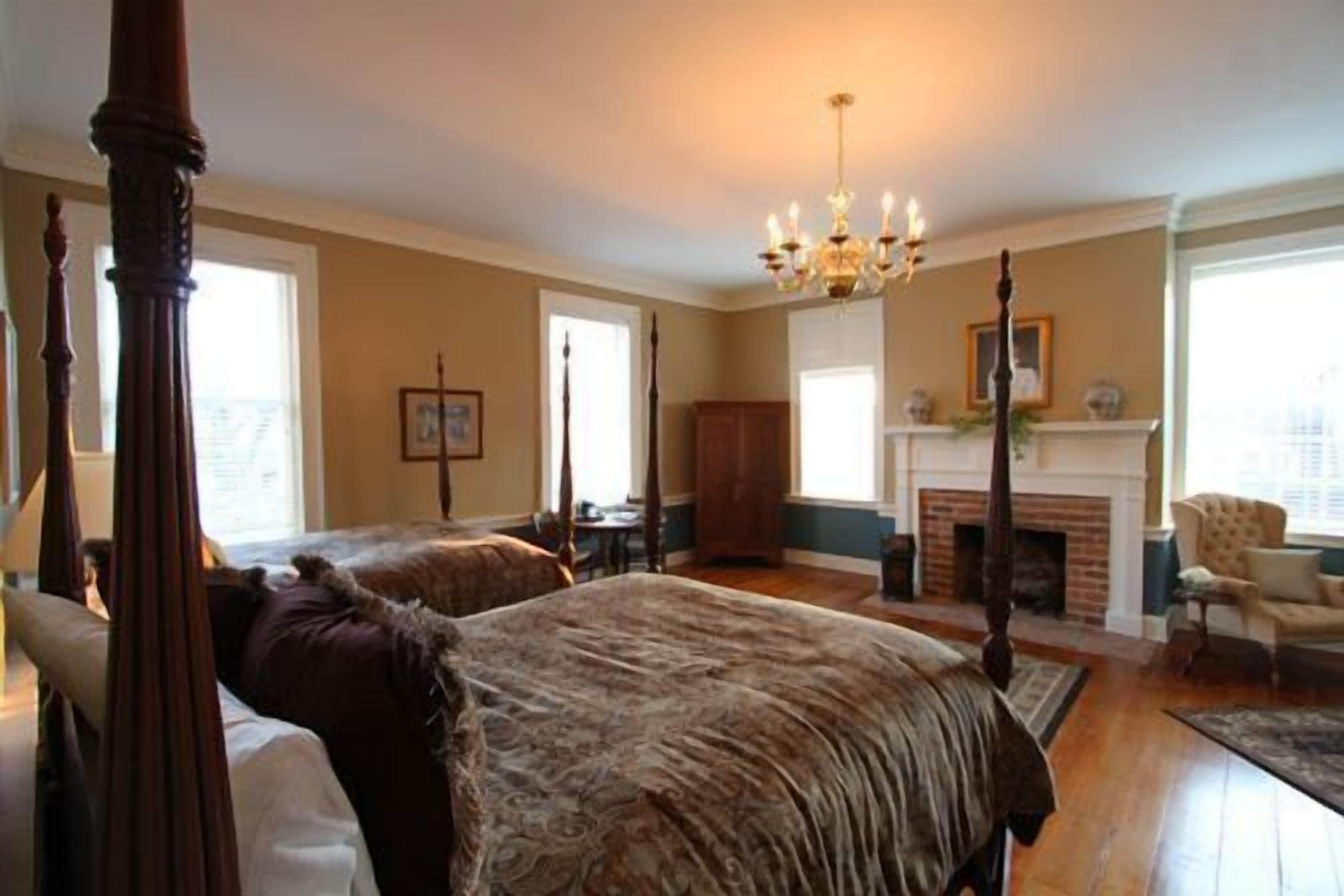 Ein geräumiges Schlafzimmer mit Himmelbett, Kamin und einer Chandelier.