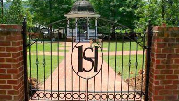 A gated entrance with a metal gate featuring a logo.