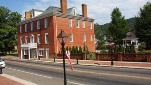 A historic brick building with a central entrance, a small balcony, and a flagpole with a flag.