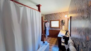A bathroom with a shower curtain, a towel rack, a sink, and a mirror. - Rock Cottage Gardens B&B (Eureka Springs)