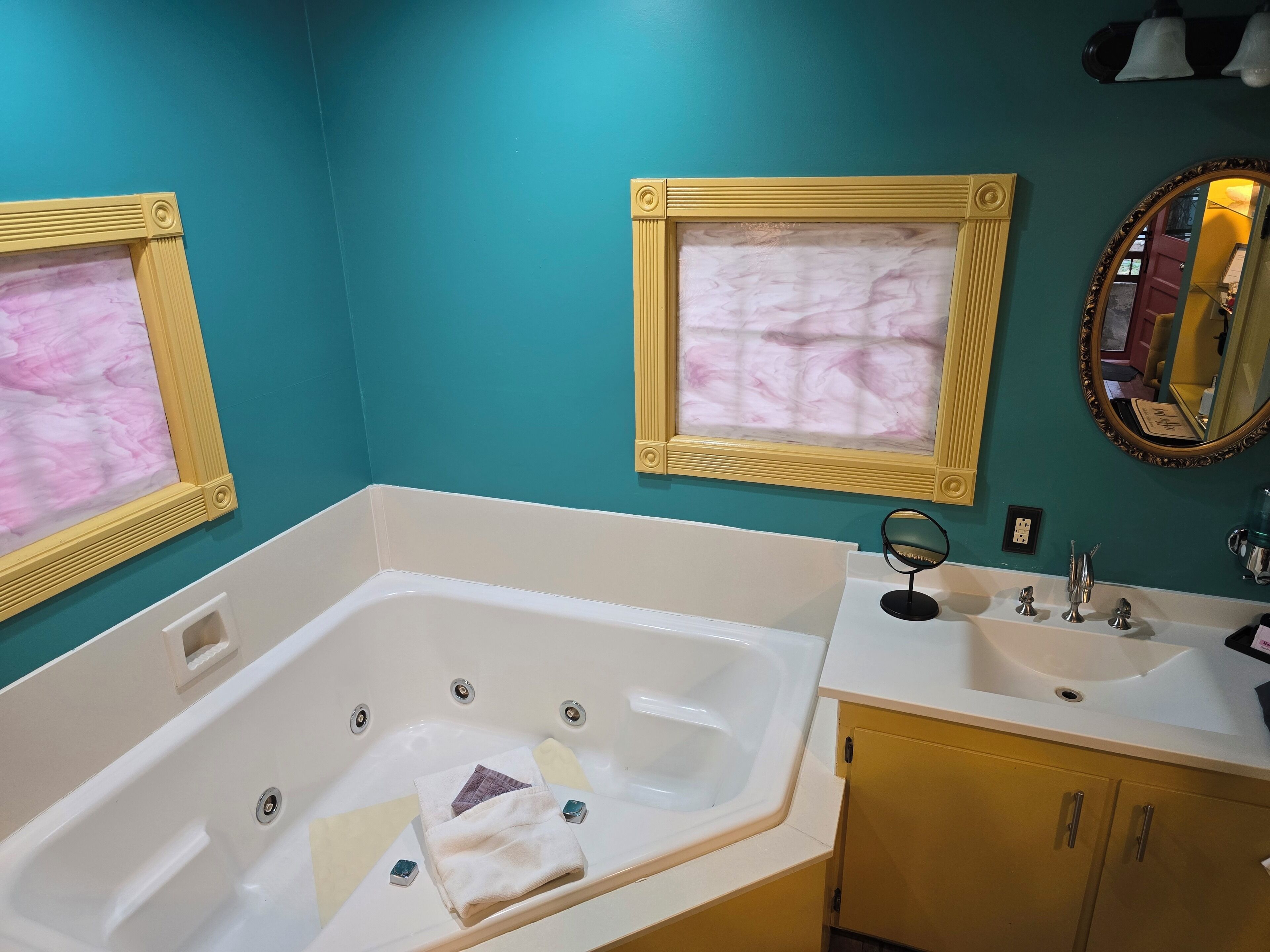 A bathroom with a bathtub, a sink, and two framed mirrors.