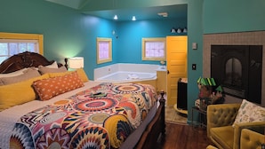 A bedroom with a large bed, a bathtub, and a fireplace. - Rock Cottage Gardens B&B (Eureka Springs)