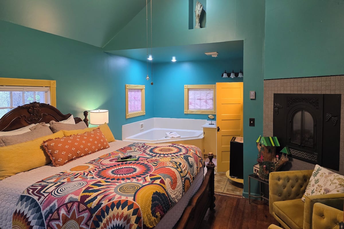 Een slaapkamer met een groot bed, een badkuip en een open haard.