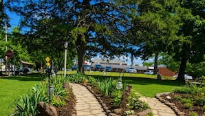 A stone pathway leading through a landscaped garden with various plants and trees. - Rock Cottage Gardens B&B (Eureka Springs)