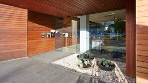 A modern building entrance with wooden paneling, glass doors, and potted plants.