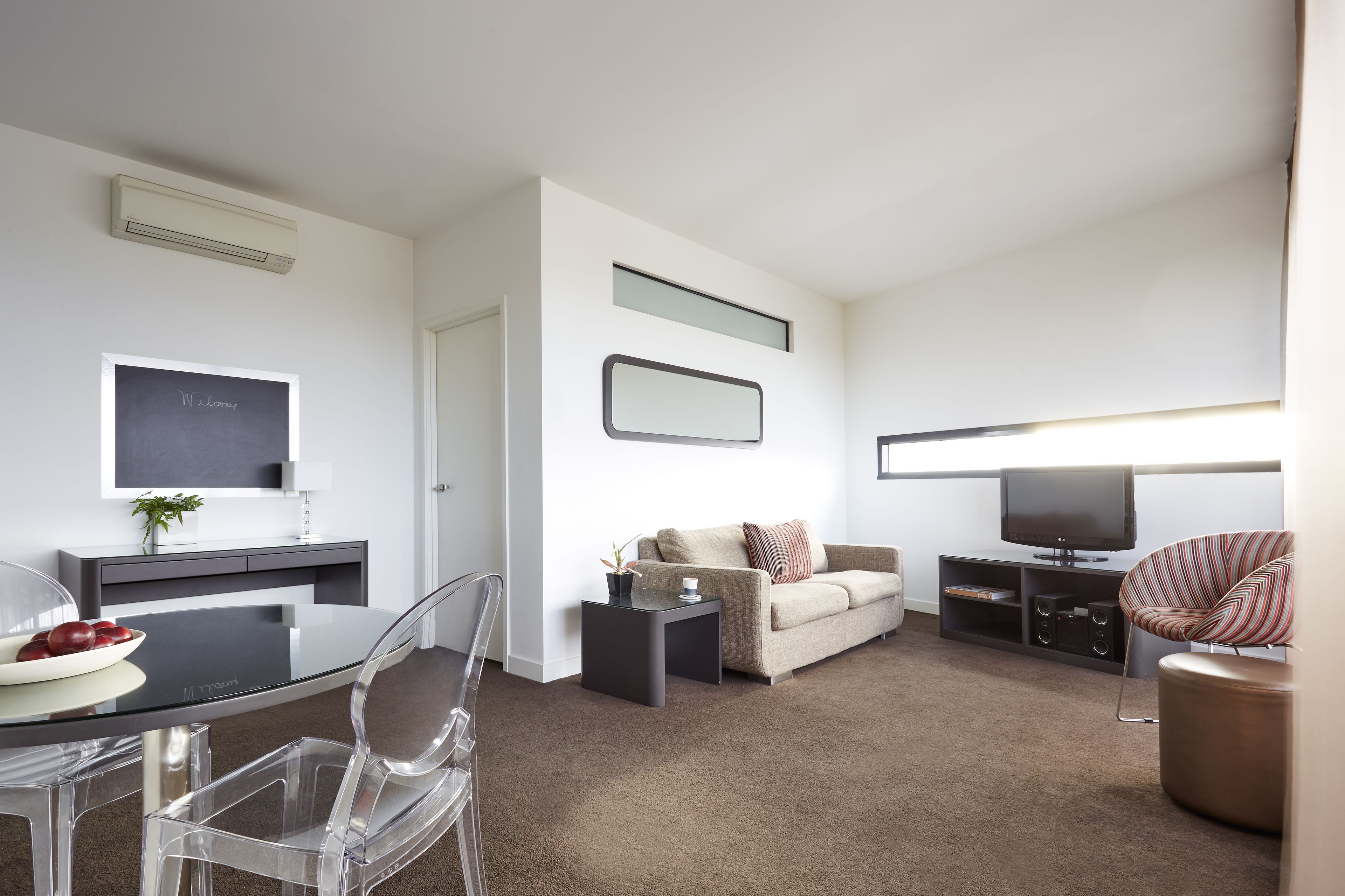 A modern living room with a dining area, a flat-screen TV, a sofa, and a coffee table.