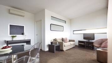 A modern living room with a dining area, a flat-screen TV, a sofa, and a coffee table.