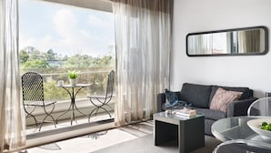 A modern living room with a balcony, a sofa, a coffee table, and a dining area with chairs and a small table.