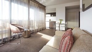 A modern living room with a sofa, striped chair, and a dining area with a table and chairs.